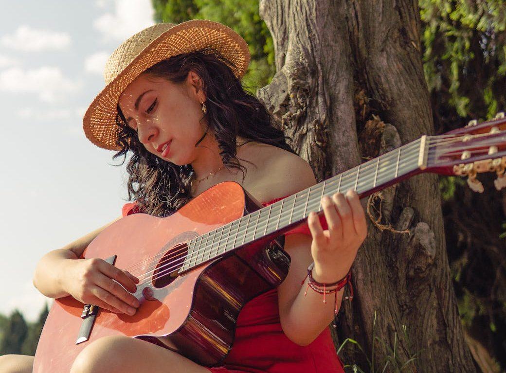 woman sitting and playing guitar